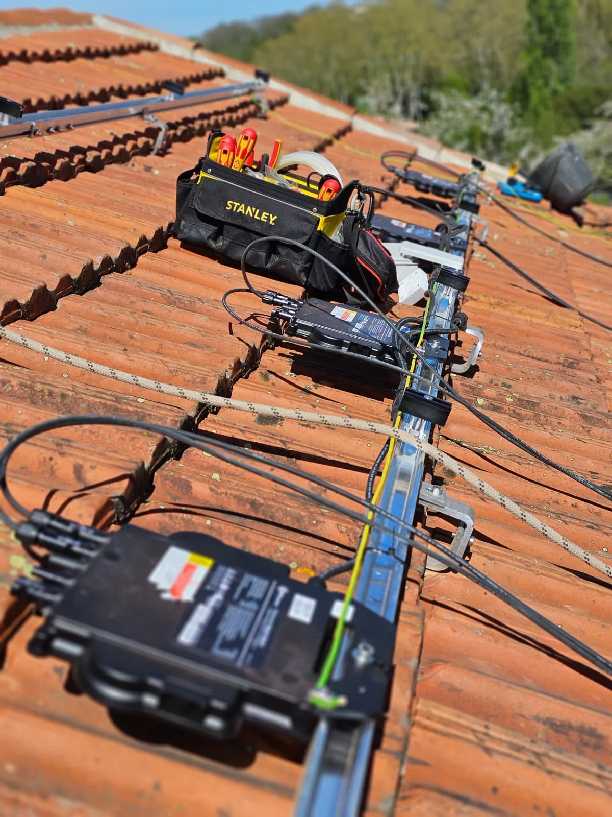 Micro-onduleurs fixés sur les rails et raccordés en série avant la pose des panneaux